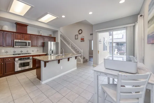 a kitchen with stainless steel appliances kitchen island granite countertop a stove a sink and a refrigerator