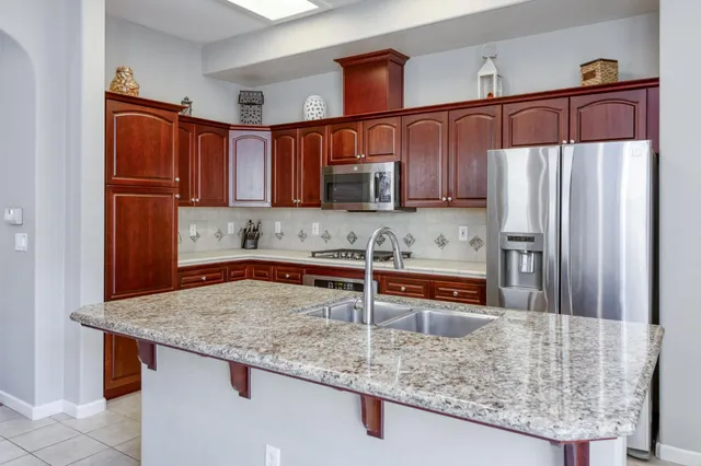 a kitchen with stainless steel appliances granite countertop a refrigerator a stove and a sink
