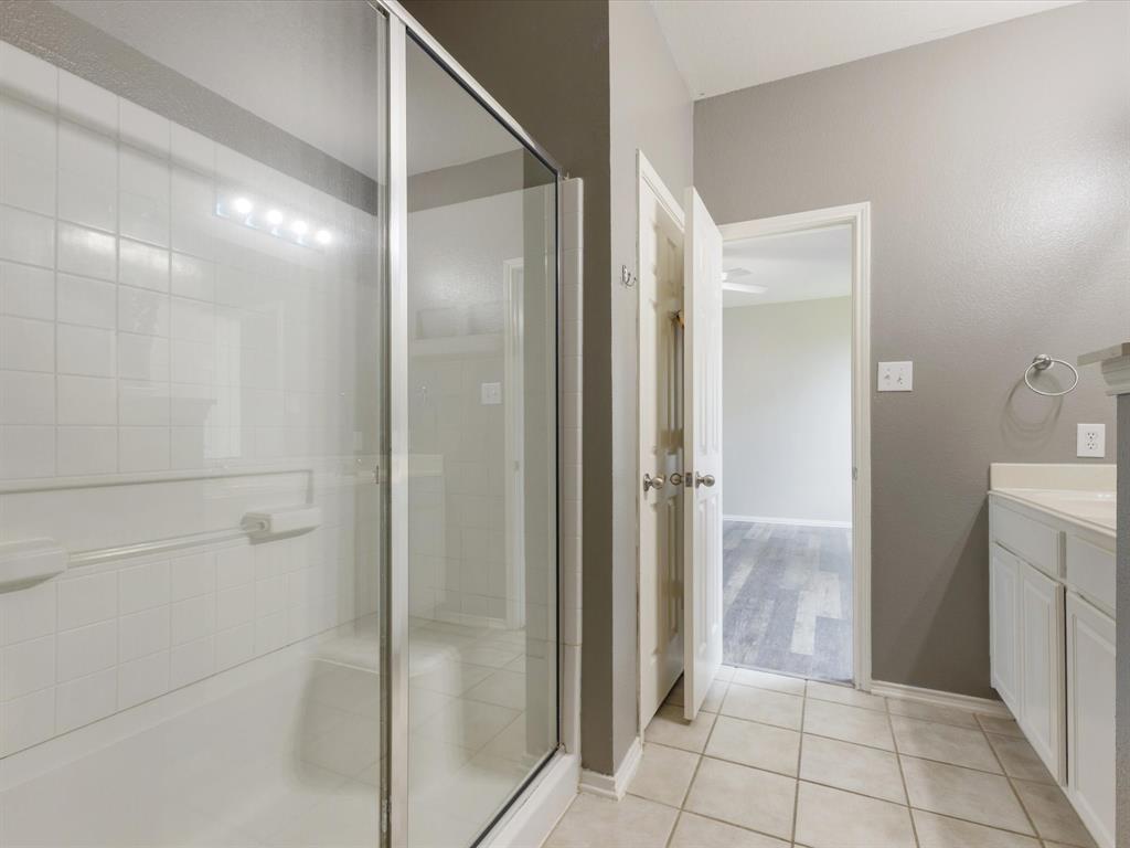 2009 Cooper Ridge Lane Heartland, TX 75126 - Photo 10 of 40 Bathroom featuring light tile patterned flooring, vanity, and a stall shower