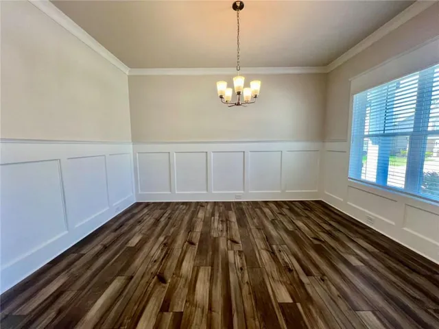 a view of an empty room with wooden floor and windows