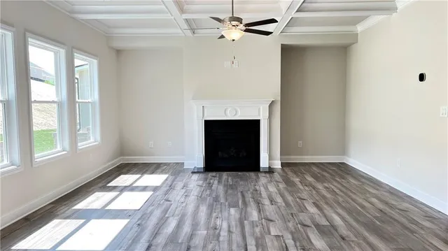 a view of an empty room with wooden floor fireplace and a window