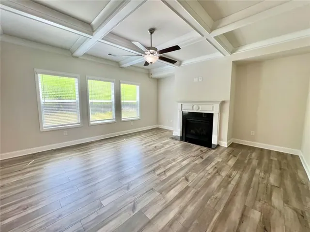 an empty room with wooden floor fireplace and windows