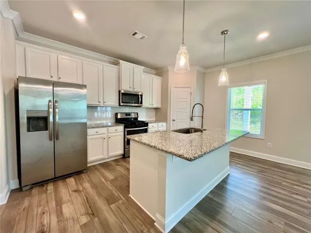 a kitchen with kitchen island granite countertop a sink refrigerator and microwave