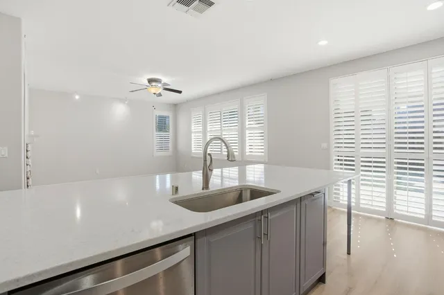 a view of an empty room with wooden floor and a ceiling fan