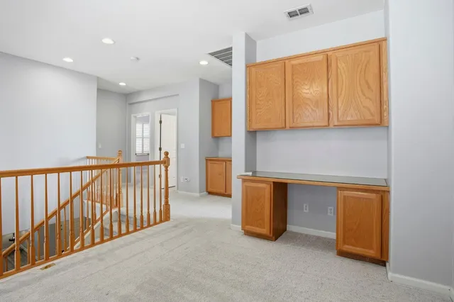 an empty room with a chandelier fan and windows