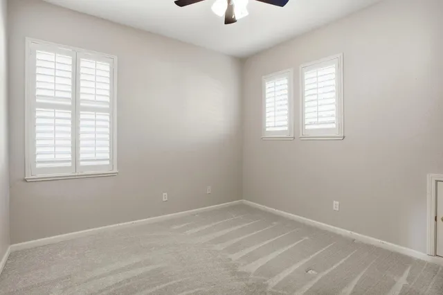 an empty room with a window and a chandelier fan