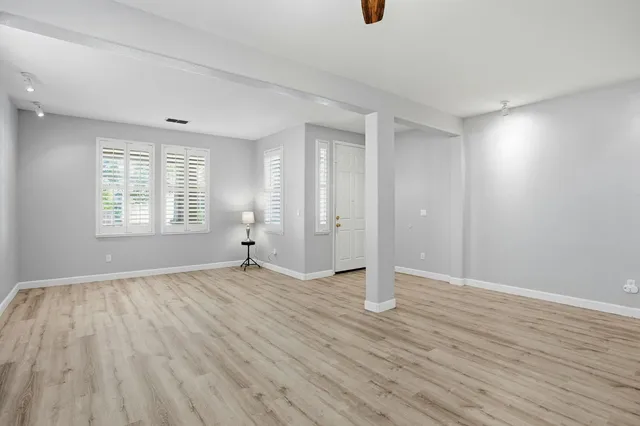 an empty room with wooden floor and windows