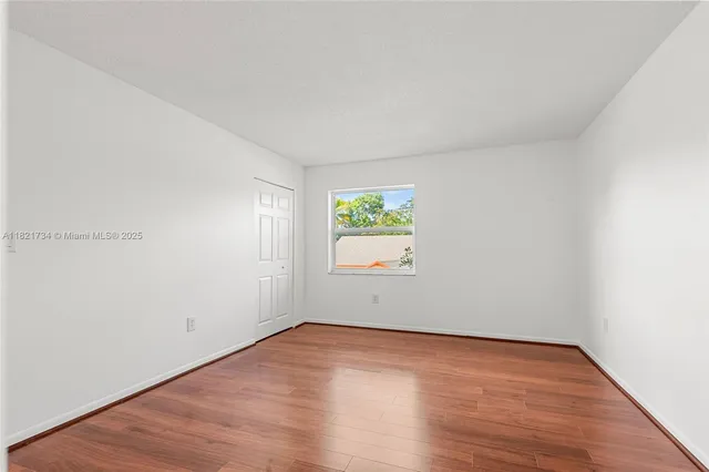 an empty room with wooden floor and window