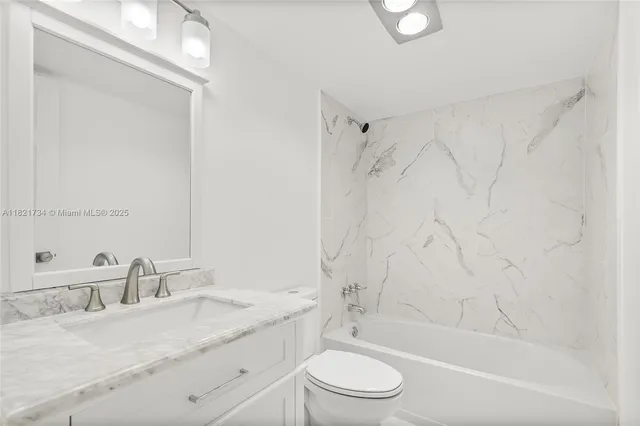 a bathroom with a granite countertop sink a toilet and shower