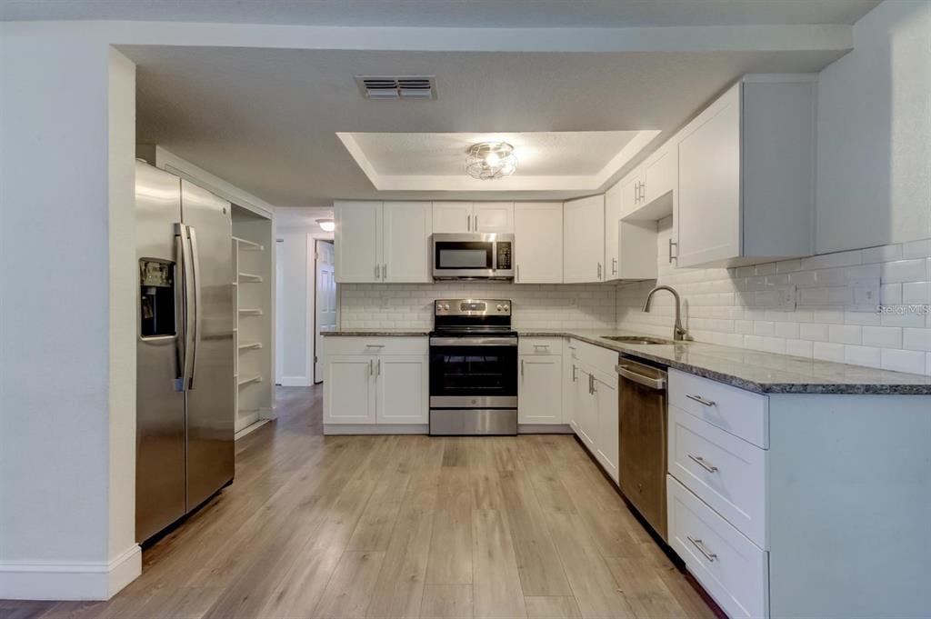 7144 Fairfax Drive Port Richey, FL 34668 - Photo 11 of 53 a kitchen with granite countertop a refrigerator and a stove top oven