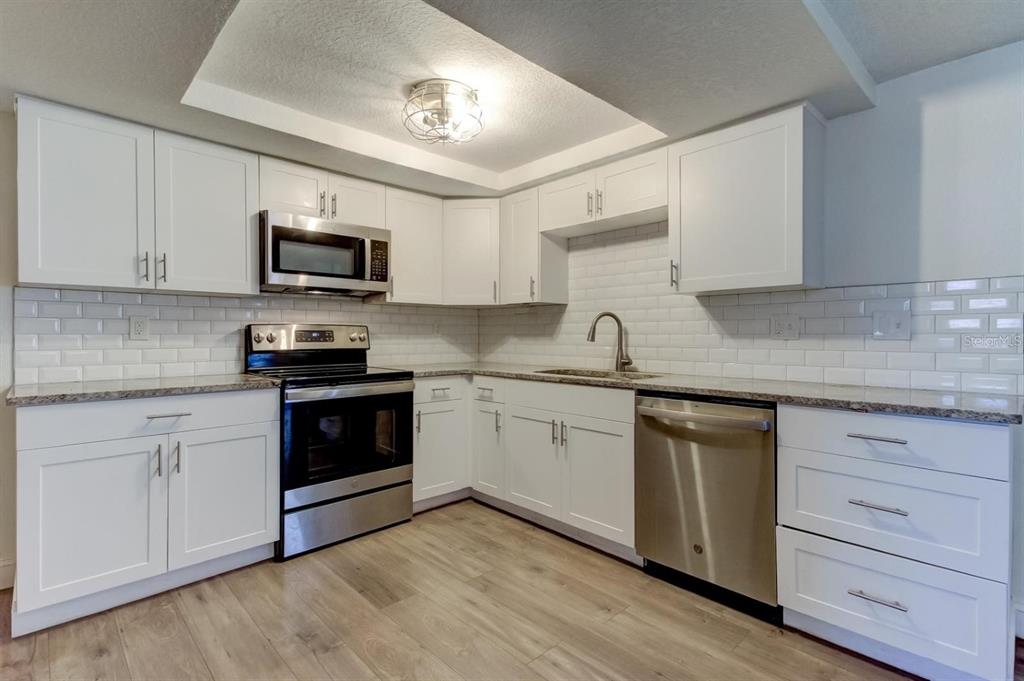 7144 Fairfax Drive Port Richey, FL 34668 - Photo 13 of 53 a kitchen with granite countertop cabinets stainless steel appliances and a sink
