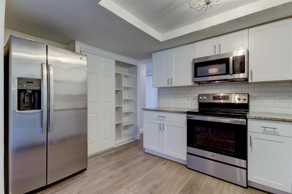 7144 Fairfax Drive Port Richey, FL 34668 - Photo 14 of 53 a kitchen with stainless steel appliances granite countertop a refrigerator and a stove top oven