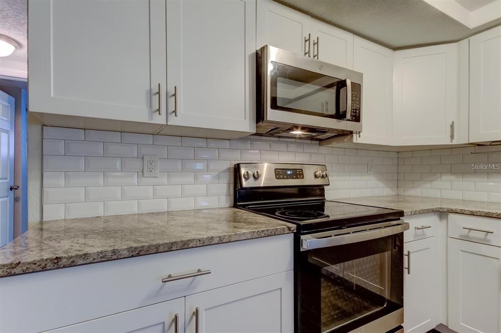 7144 Fairfax Drive Port Richey, FL 34668 - Photo 16 of 53 a kitchen with granite countertop a stove and a microwave