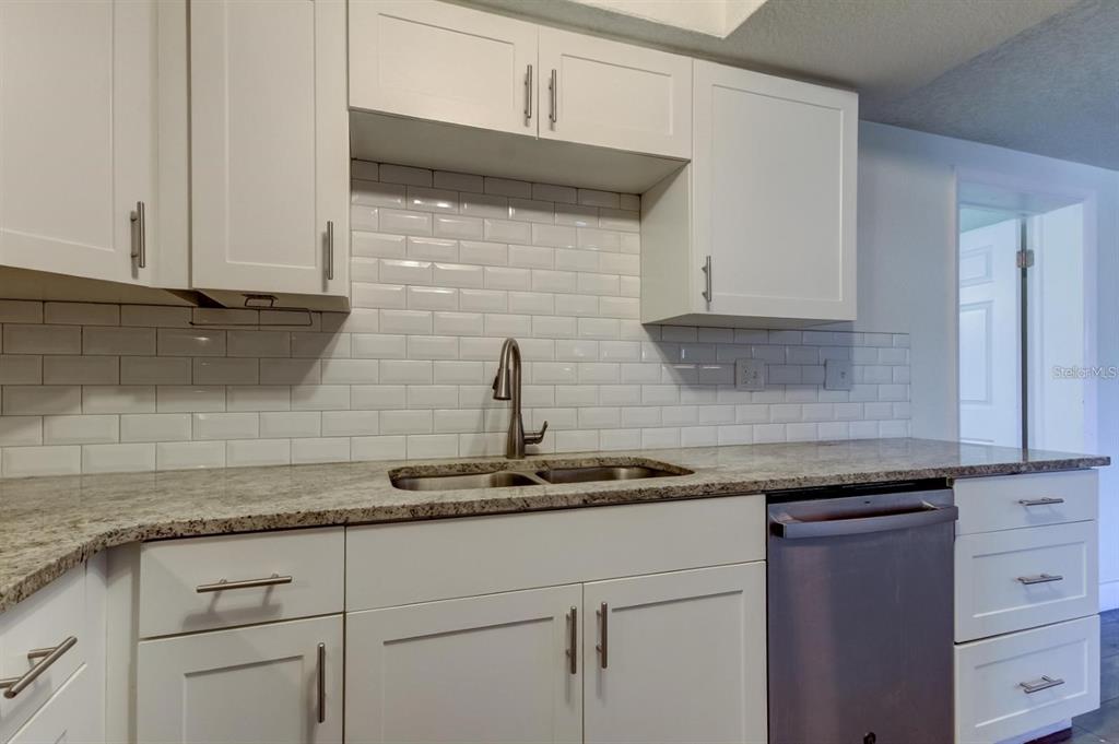 7144 Fairfax Drive Port Richey, FL 34668 - Photo 17 of 53 a kitchen with granite countertop white cabinets and white appliances