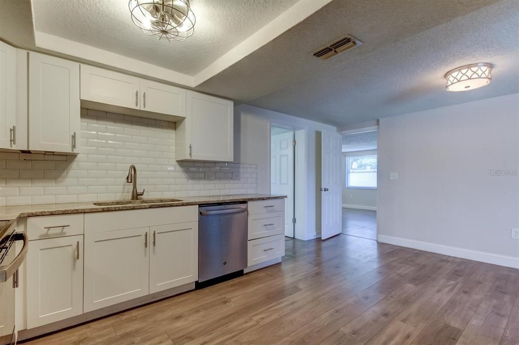 7144 Fairfax Drive Port Richey, FL 34668 - Photo 18 of 53 a kitchen with granite countertop white cabinets and white appliances