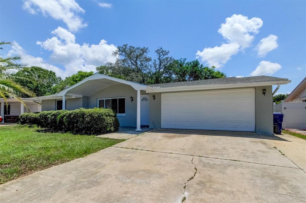 7144 Fairfax Drive Port Richey, FL 34668 - Photo 2 of 53 a front view of a house with a yard and garage