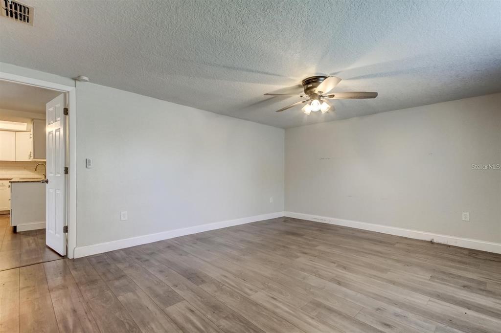 7144 Fairfax Drive Port Richey, FL 34668 - Photo 23 of 53 an empty room with wooden floor and a ceiling fan