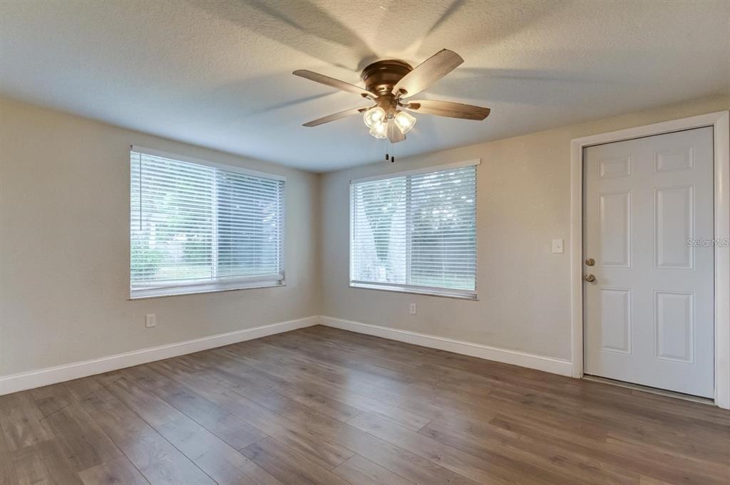 7144 Fairfax Drive Port Richey, FL 34668 - Photo 27 of 53 a view of a livingroom with a ceiling fan wooden floor and a window