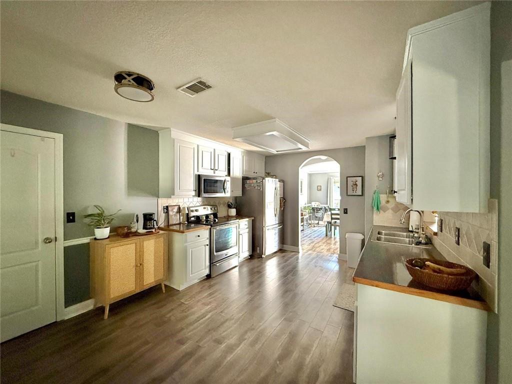 1071 Covenant Court Bethlehem, GA 30620 - Photo 3 of 20 a kitchen with stainless steel appliances a stove top oven a sink a refrigerator white cabinets and wooden floor