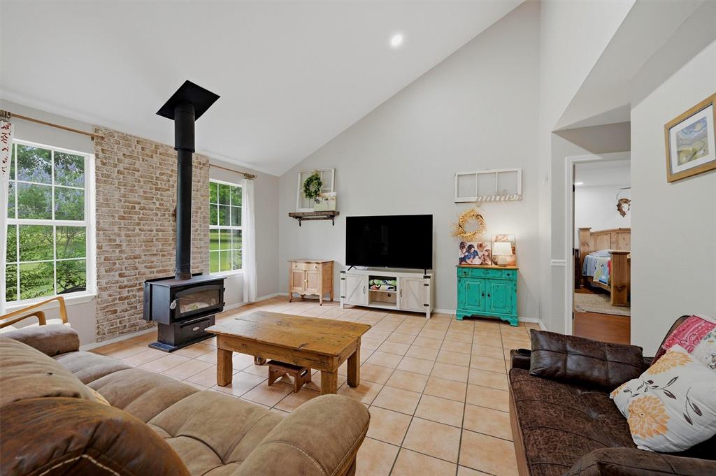 905 Crawford Road Sadler, TX 76264 - Photo 5 of 40 Spacious living area featuring a vaulted ceiling and a wood-burning stove with a brick-finish surround