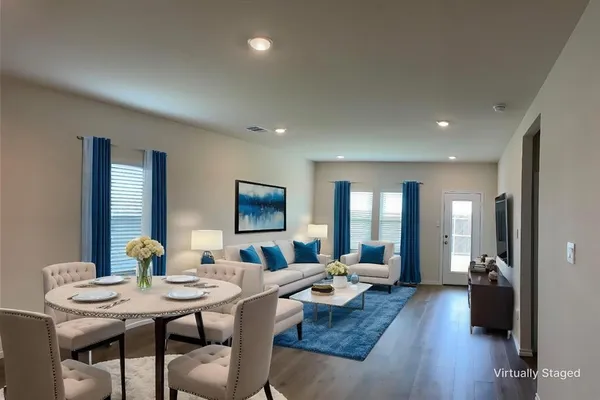 a living room with furniture kitchen view and a wooden floor