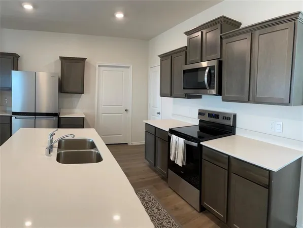 a kitchen with a sink and a stove top oven with wooden floor