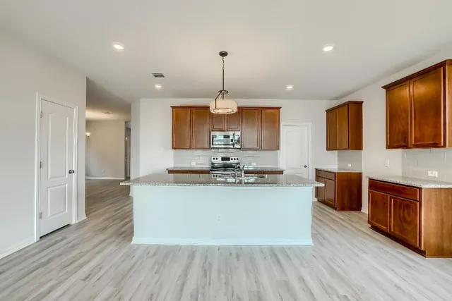 a large kitchen with stainless steel appliances granite countertop a stove and a wooden floors