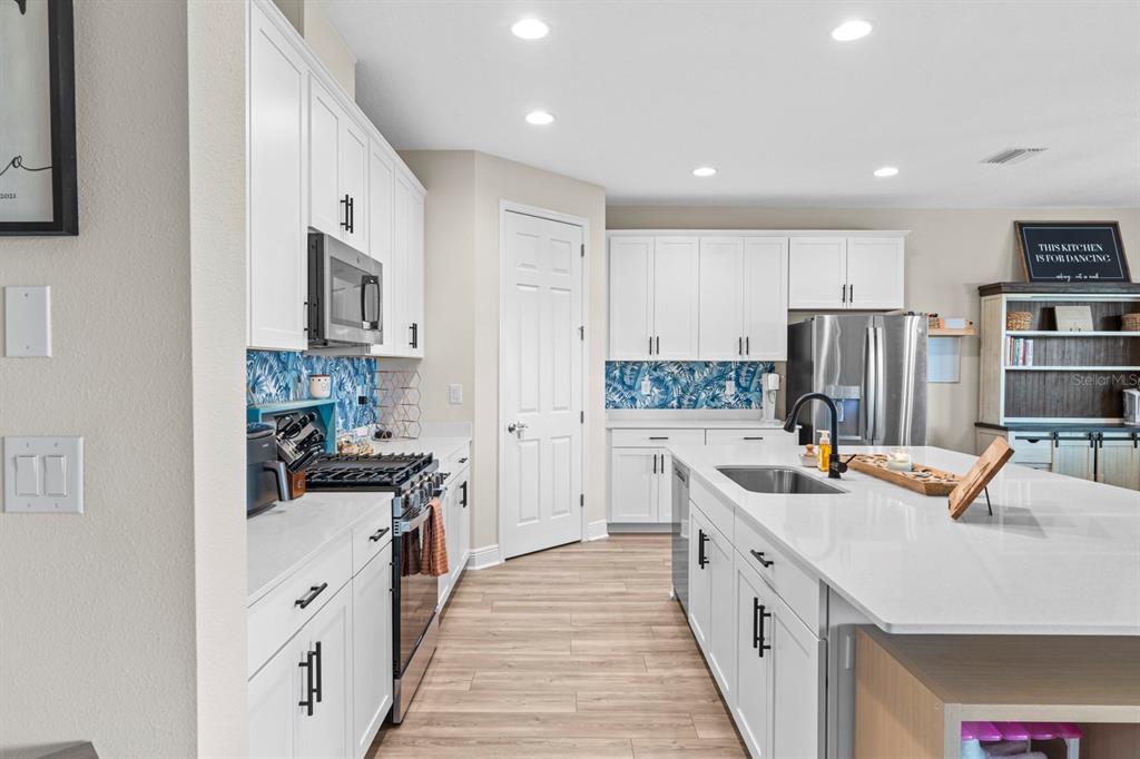 14661 Horse Trot Road Lithia, FL 33547 - Photo 11 of 46 a kitchen with stainless steel appliances a stove oven a sink a refrigerator white cabinets and wooden floor