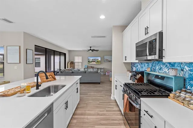 a kitchen with stainless steel appliances a stove a sink dishwasher a refrigerator a oven and white cabinets