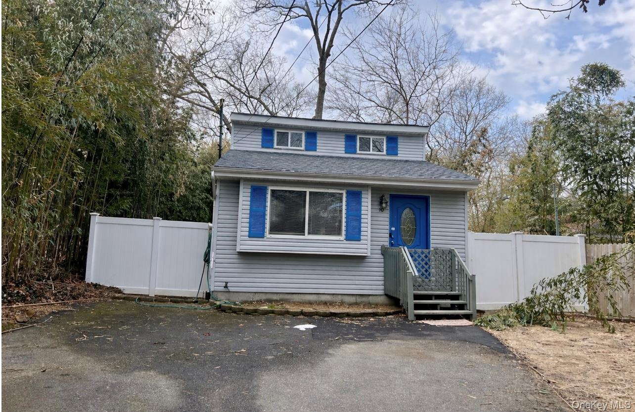 10 Rutland Road Mastic, NY 11950 - Photo 3 of 12 front view of house with a bench and table and potted plants