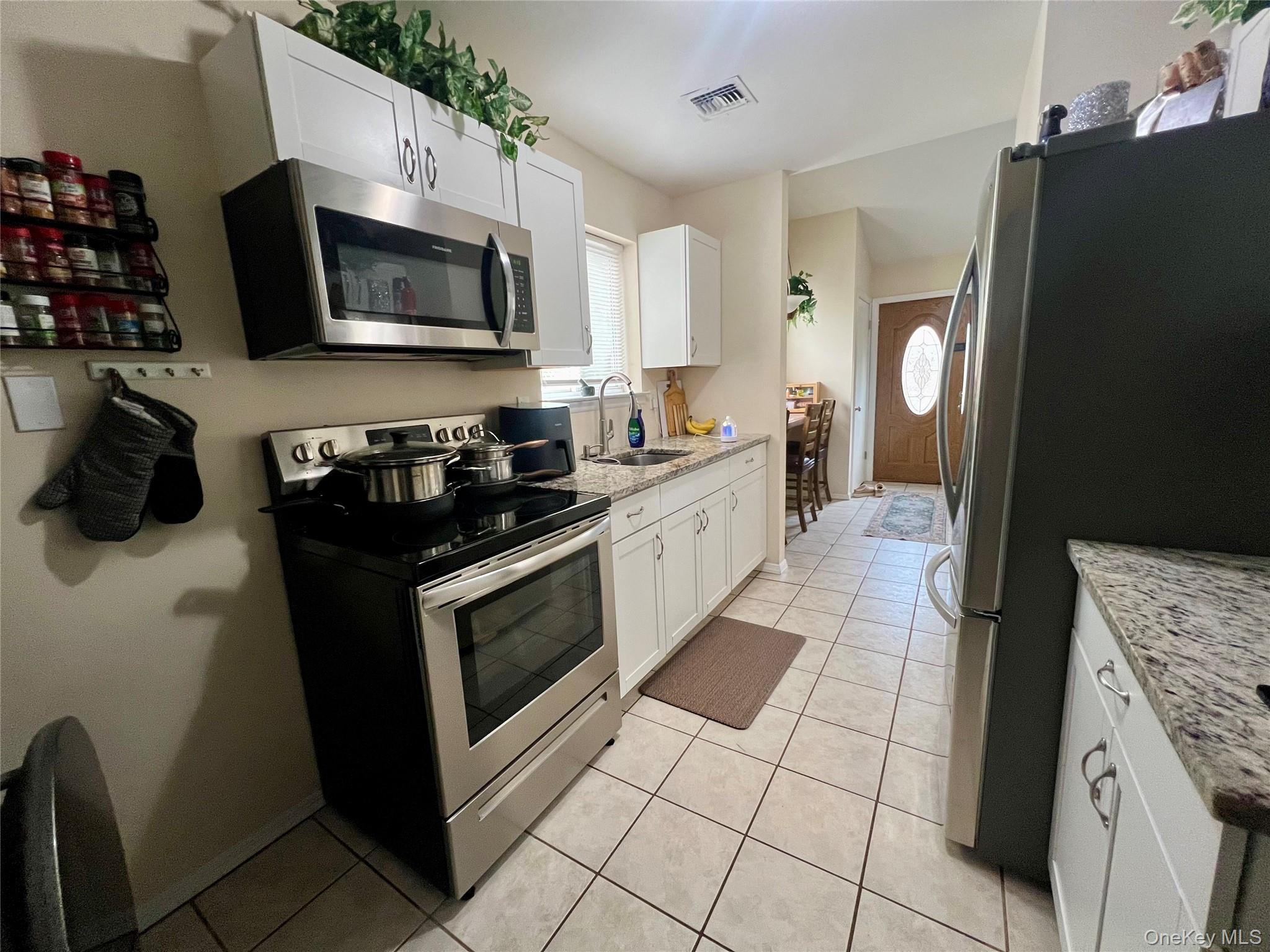 10 Rutland Road Mastic, NY 11950 - Photo 9 of 12 a kitchen with stainless steel appliances granite countertop a refrigerator a stove top oven a sink and dishwasher