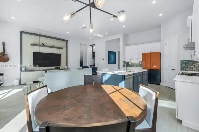 a large kitchen with a table chairs refrigerator and a sink