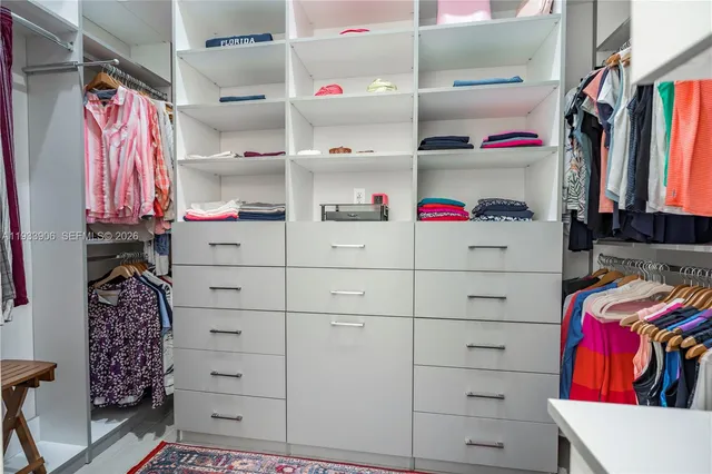 a view of walk in closet with clothes and shoes