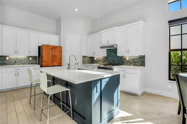 a kitchen with stainless steel appliances kitchen island granite countertop a table chairs sink and cabinets