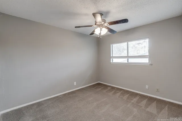 an empty room with a window and a fan