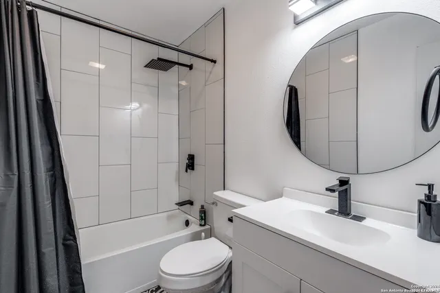 a bathroom with a sink a toilet and shower a mirror