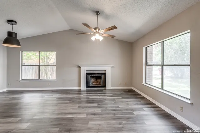 a view of an empty room with window and chandelier fan