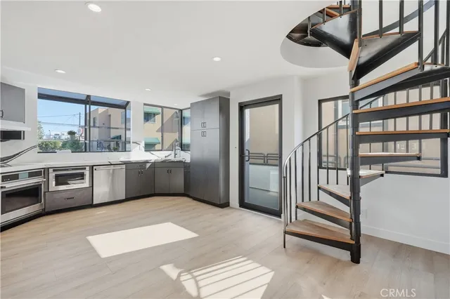 a large kitchen with a large counter top space a sink stainless steel appliances and cabinets