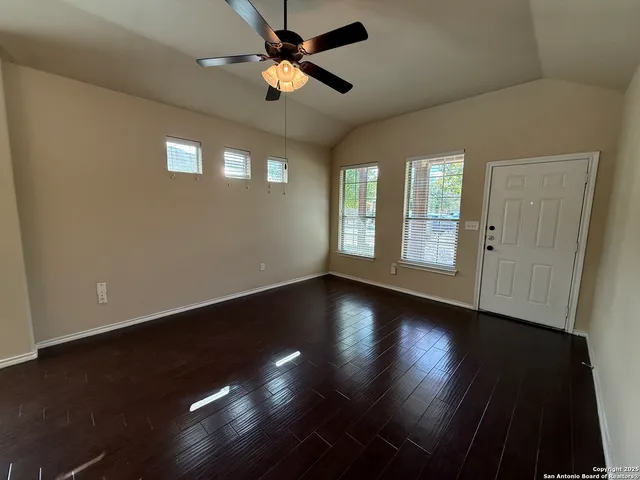 an empty room with wooden floor fan and windows