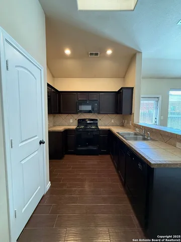 a large kitchen with stainless steel appliances a large counter top a stove and a refrigerator