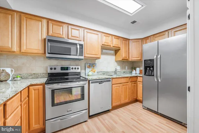 a kitchen with stainless steel appliances granite countertop a refrigerator stove microwave and sink