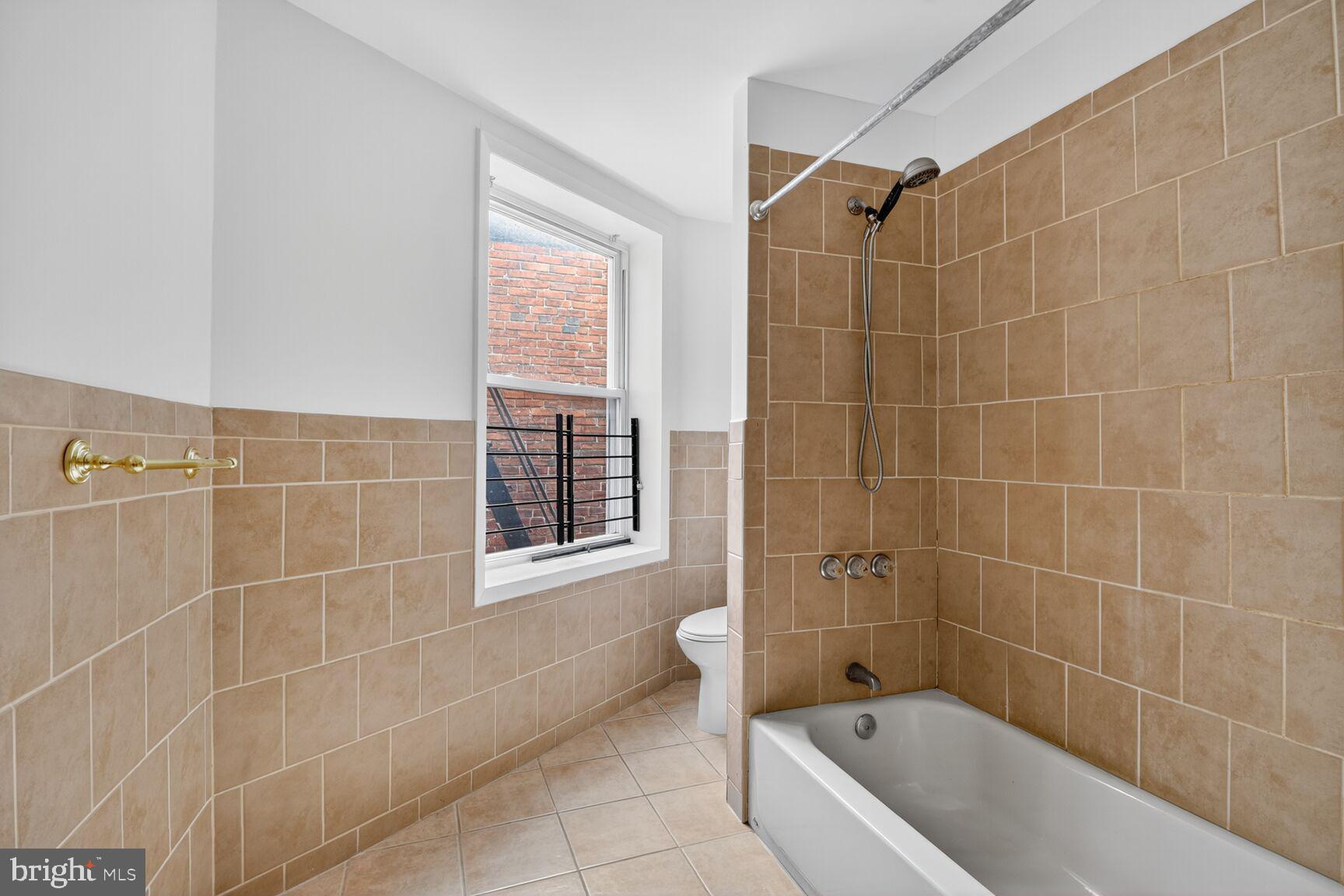 1404 Madison Avenue Baltimore, MD 21217 - Photo 12 of 54 a bathroom with a bathtub a window and a shower