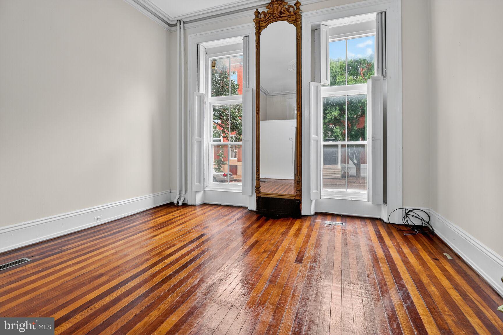 1404 Madison Avenue Baltimore, MD 21217 - Photo 3 of 54 a view of an empty room with exposed radiator and wooden floor