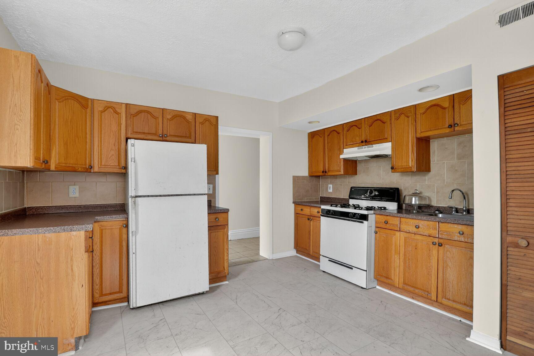 1404 Madison Avenue Baltimore, MD 21217 - Photo 39 of 54 a kitchen with a refrigerator a stove top oven a sink and dishwasher