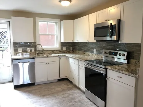 a kitchen with stainless steel appliances granite countertop a stove a sink and a microwave
