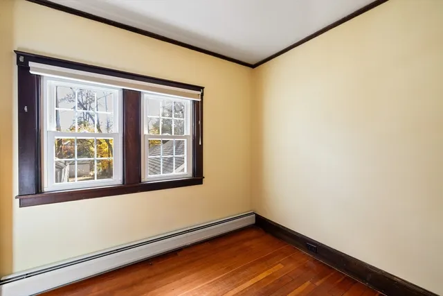 a view of an empty room with window and wooden floor