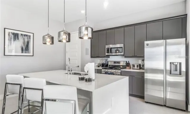 a kitchen with stainless steel appliances a table chairs refrigerator and microwave