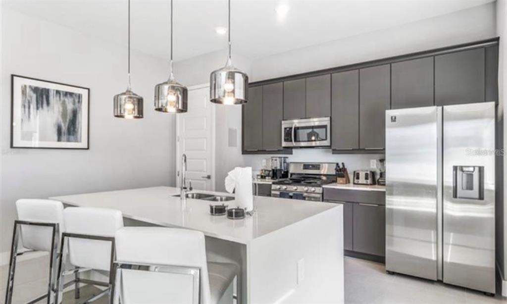 7773 Spectrum Drive Reunion, FL 34747 - Photo 11 of 14 a kitchen with stainless steel appliances a table chairs refrigerator and microwave