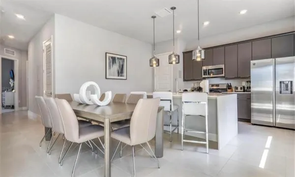 a dining room with kitchen island a table chairs a refrigerator and a kitchen view