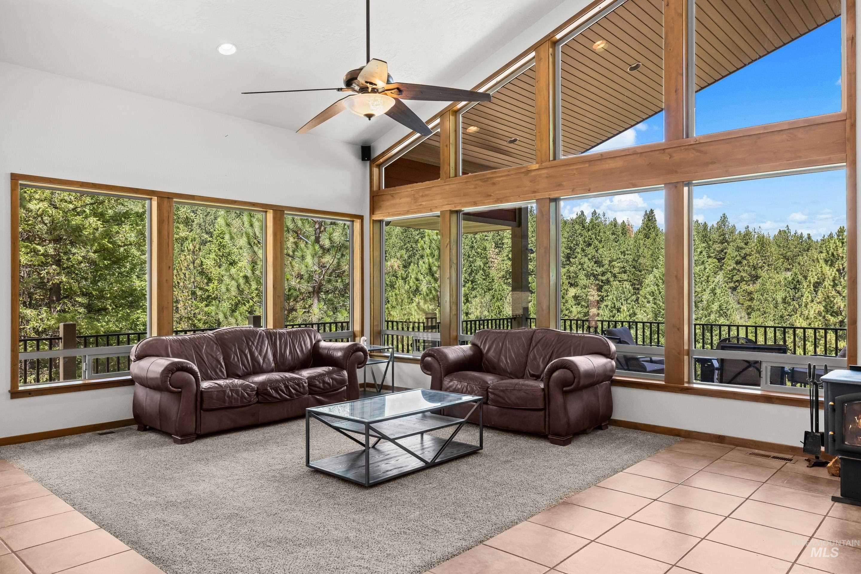 92 Cruickshank Road Horseshoe Bend, ID 83629 - Photo 10 of 50 Living area featuring a vaulted ceiling with exposed wood beams, a ceiling fan, and large windows with natural wood trim